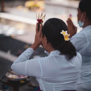 a woman sitting on the ground with a flower in her hair